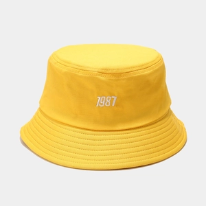 Close-up of a vibrant yellow bucket hat with white 1987 embroidery and reinforced stitching