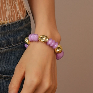 Close-up of bohemian acrylic beads bracelet with purple rings and golden metal accents