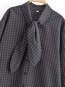 Détail d'une chemise à carreaux gris et jaune montrant le nœud et la texture du tissu
