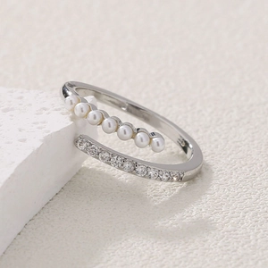 Adjustable open ring with micro-paved pearls and zircons on a white stone background