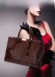 Detail showing brown crocodile pattern tote bag with gold metal clasp and luxury texture