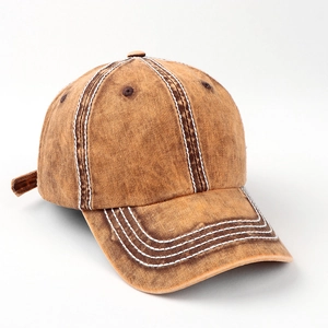 Macro detail of brown cotton baseball cap showing white stitching and washed denim texture