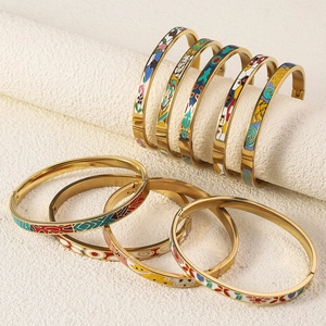 Detail of 18K gold plated titanium bangles featuring colorful enamel geometric patterns