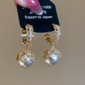 Detail of vintage gold-plated pearl drop earrings with crystal micro-pave hoop and filigree cap