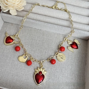 Detail of 18k gold plated necklace featuring red heart pendants and a love charm
