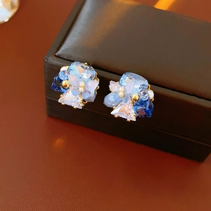 Macro detail of blue crystal flower stud earrings with gold claw setting and pearls