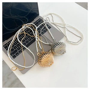 Detail of shell-shaped acrylic evening bags with pearl and metal chains in gold and silver