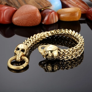 Macro view of gold punk skull bracelet featuring detailed stainless steel woven links