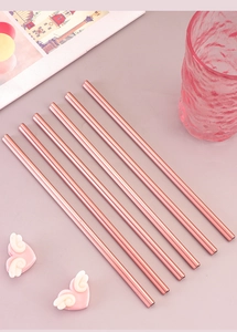 Detailed view of six rose gold stainless steel straws on a pink aesthetic background