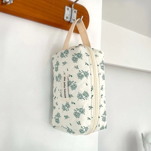 Detail of quilted cotton floral cosmetic bag hanging on a hook with woven strap