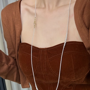 Detail of long pearl necklace with golden S-hook clasp and round white pearls