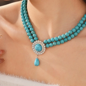 Close-up of a double-layer turquoise beaded necklace with rhinestone pavé pendant and drop