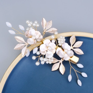 Traditional bridal hair clip with gold flowers, pearls, and tassels on a luxury blue plate