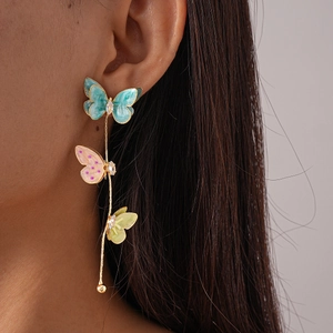 Gros plan de boucles d'oreilles longues en or avec papillons colorés et zircons sur mannequin