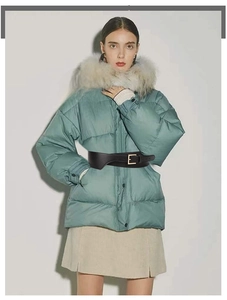 Detail of a black elastic waist belt with a gold rectangular buckle on a puffer jacket
