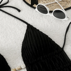 Detail of black ribbed bikini top with ivory beads on fuzzy white beach decor
