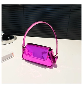Detail of glossy hot pink patent leather mini handbag on a minimalist white surface