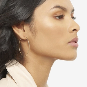Close-up of a model wearing large gold hoop earrings made of s925 silver needles