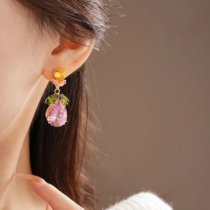 Close-up of elegant gold earrings set with multicolored pear-cut zircons on a model