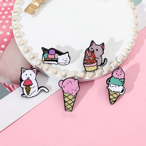 Close-up of five colorful enamel cat brooches with ice cream cones on a pink surface