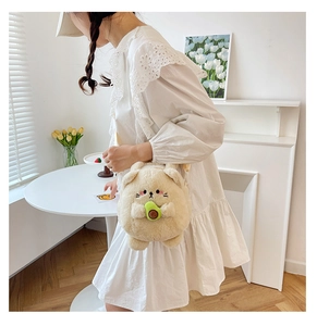 Plush cat crossbody bag with avocado detail shown on model in bright indoor setting