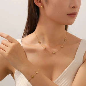 Detail of gold-plated sun and moon star charms with inset diamonds on model neck and wrist