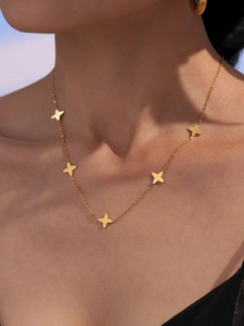 Golden double-layer necklace featuring five clover charms on model's neckline