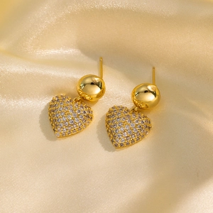 Elegant gold heart earrings with zircon inlay on luxury champagne silk background