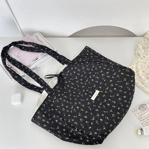 Detailed top view of a black floral tote bag with yellow flowers and lifestyle props