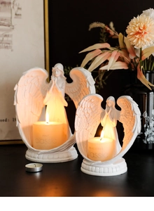 Detailed view of two white resin angel candle holders in a romantic home decor setting