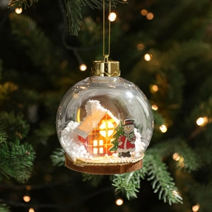 Bola de Navidad LED transparente con cabaña roja y muñeco de nieve en el árbol