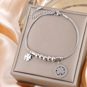 Macro shot of silver steel clover pendant bracelet on a grey luxury jewelry box