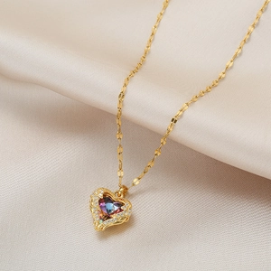 Golden heart pendant necklace with colorful gemstone and petal chain on beige fabric