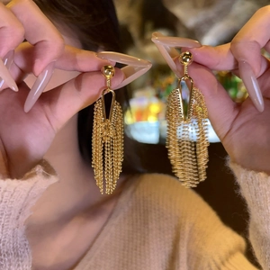 Close-up of elegant gold long fringe tassel earrings featuring vintage geometric details
