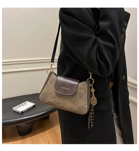 Detail view of contrast stitching handbag with gold hardware and tennis racket charm