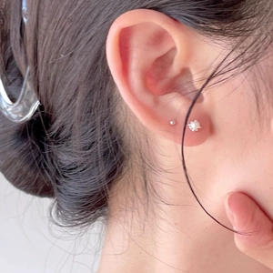 Macro shot of minimalist 925 sterling silver pearl stud earrings on model ear