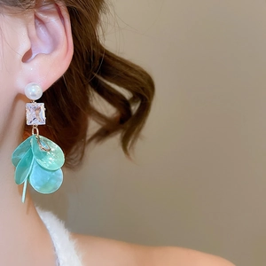 Detailed close-up of long tassel earrings with white pearl, zircon, and green shell leaves