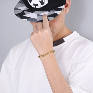 Detail of gold stainless steel geometric chain bracelet on a model wearing white t-shirt