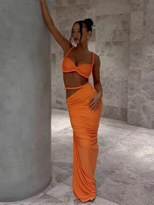 Two-piece vibrant orange set with twist strap crop top and high-waist side-slit maxi skirt
