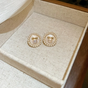 Gros plan sur des boucles d'oreilles élégantes bordées de perles avec un nœud doré.
