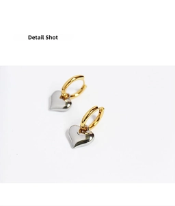 Detail shot of two-tone gold and silver heart-shaped pendant earrings with polished finish