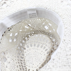 Macro shot of 100% paper fiber weave texture and care label inside white straw hat
