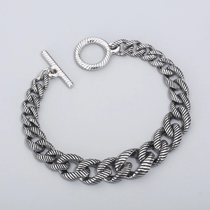 Macro detail of silver stainless steel Cuban chain bracelet with twisted texture and OT clasp