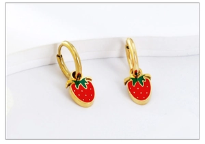 Detailed view of red strawberry drop earrings with golden hoops and green leaves