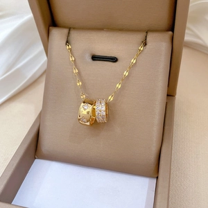Detail of gold double-ring pendant necklace with pavé crystals on a jewelry box
