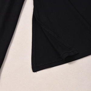 Detail shot of the side slit design on a black long-sleeved pleated fashion top