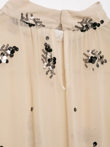 Detail of beige sheer blouse featuring black and silver sequin floral embroidery