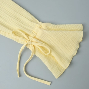 Detail of light yellow flared cotton sleeve with elastic cuff and self-tie drawstring bow