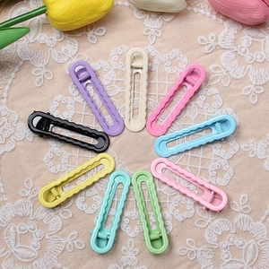 Detailed arrangement of wave-shaped macaron hair clips on beige lace with tulips