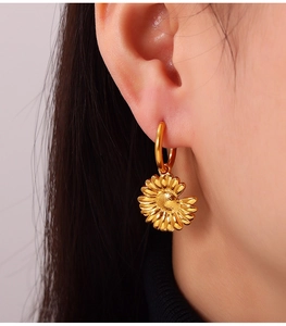 Macro detail of a 18K gold plated sunflower pendant earring on woman's ear